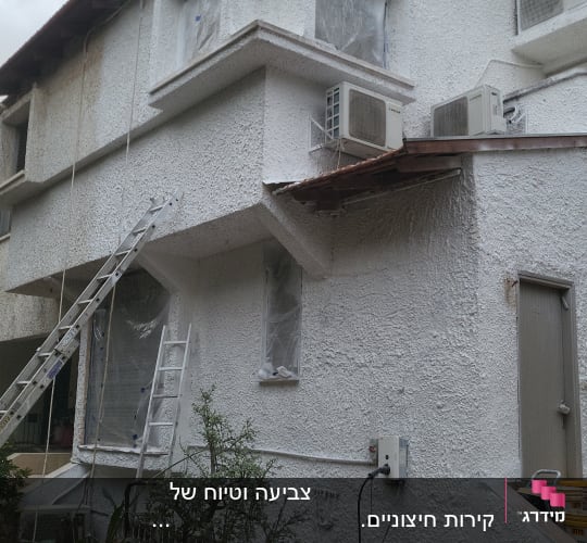 בית עם קירות צבועים בלבן, סולמות ומזגנים